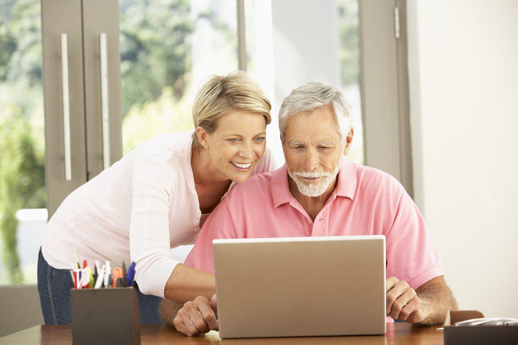 Adult Daughter And Senior Father Using Laptop At Home
